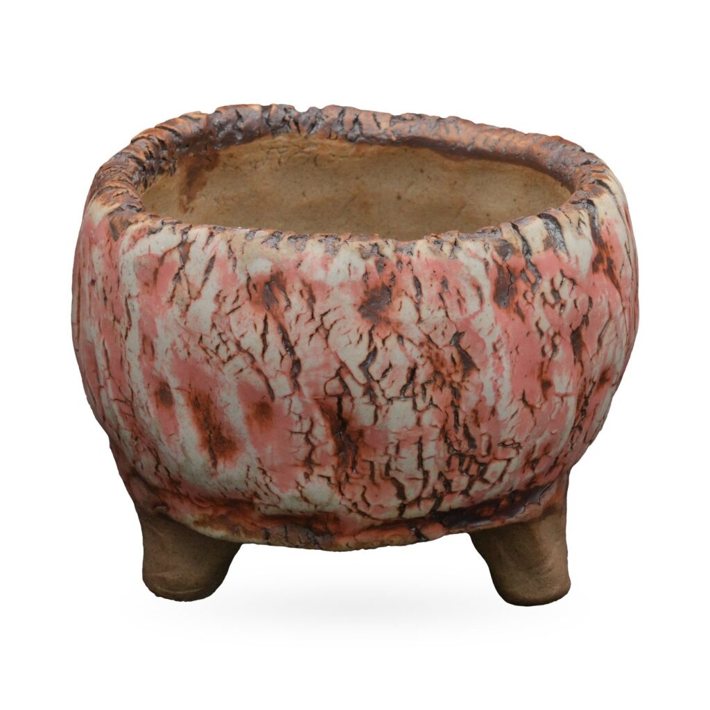 Round coral-pink and cream bark-texture crackle-glaze pot on small unglazed clay feet
