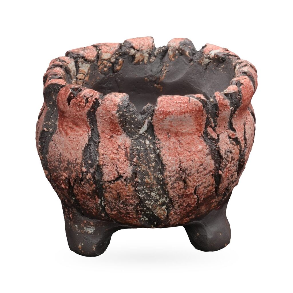 Round coral-pink and charcoal striped textured pot with scalloped rim and small dark feet