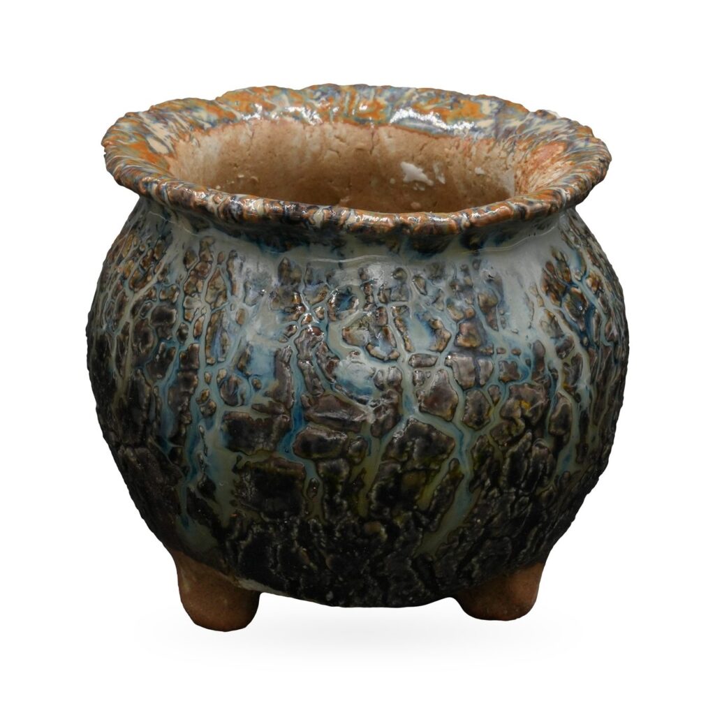 Round footed pot in dark teal and charcoal crackle glaze with a textured rust and blue rolled rim