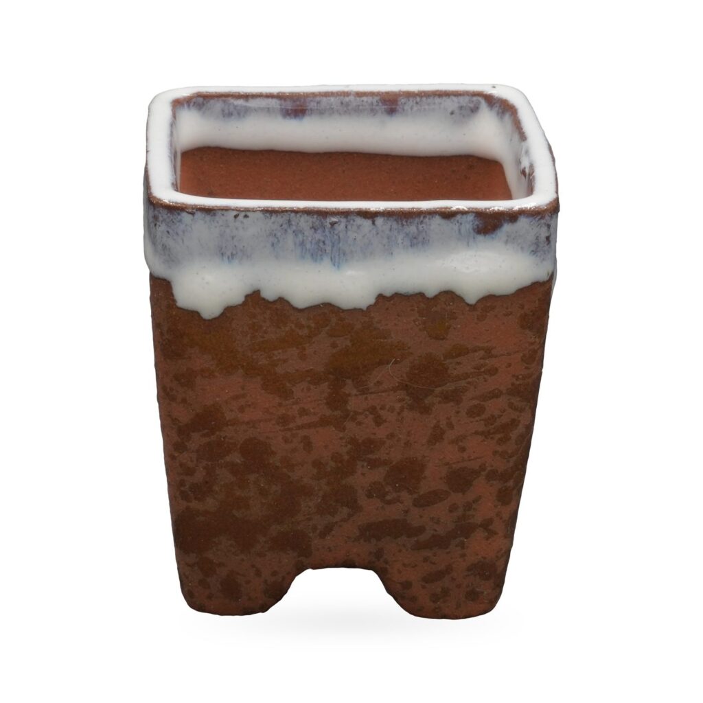 Speckled rust-brown square footed pot with glossy white drip glaze around the rim