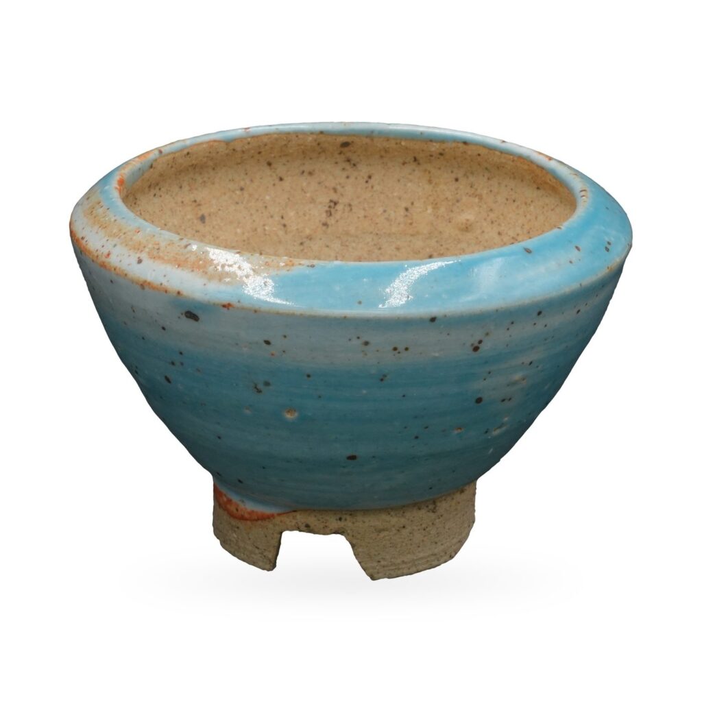 Wide footed bowl pot in speckled glossy sky-blue glaze with a sandy interior and clay feet