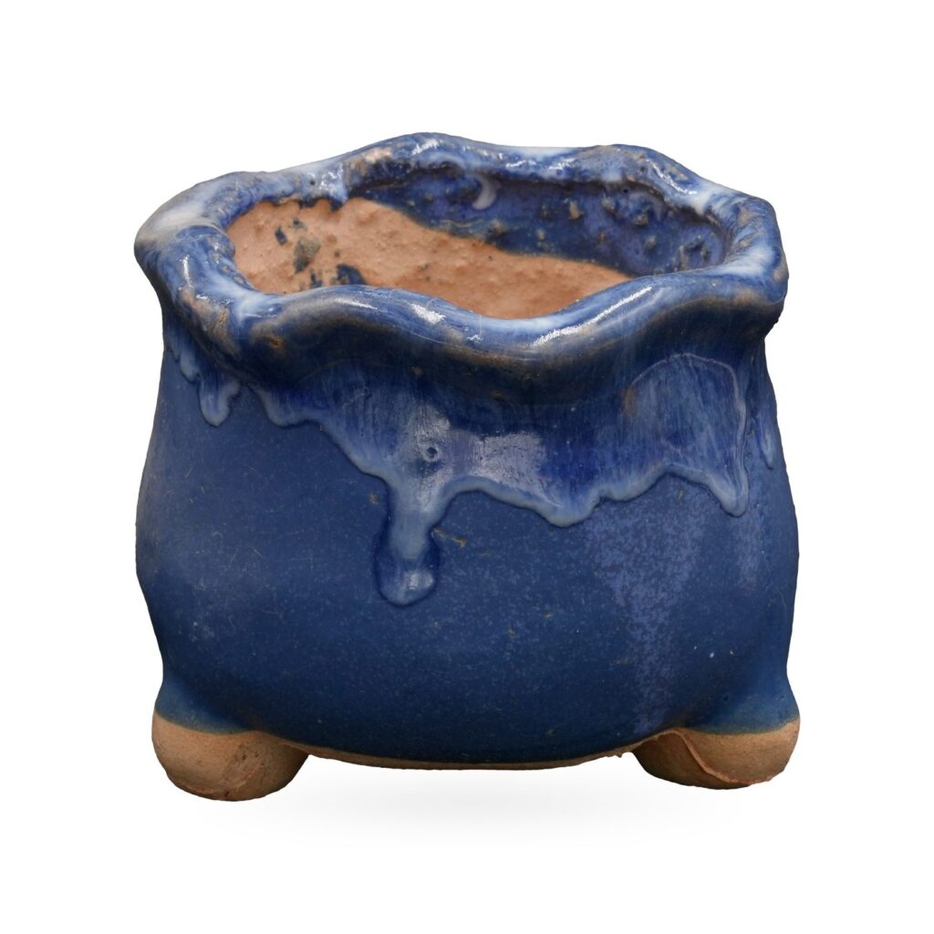 Cobalt blue footed pot with a wavy rim and glossy blue and white glaze drips from the rim