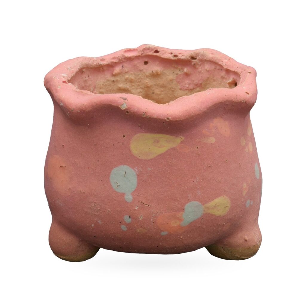 Matte coral pink footed pot with a wavy rim and pale blue, yellow and peach splatter spots