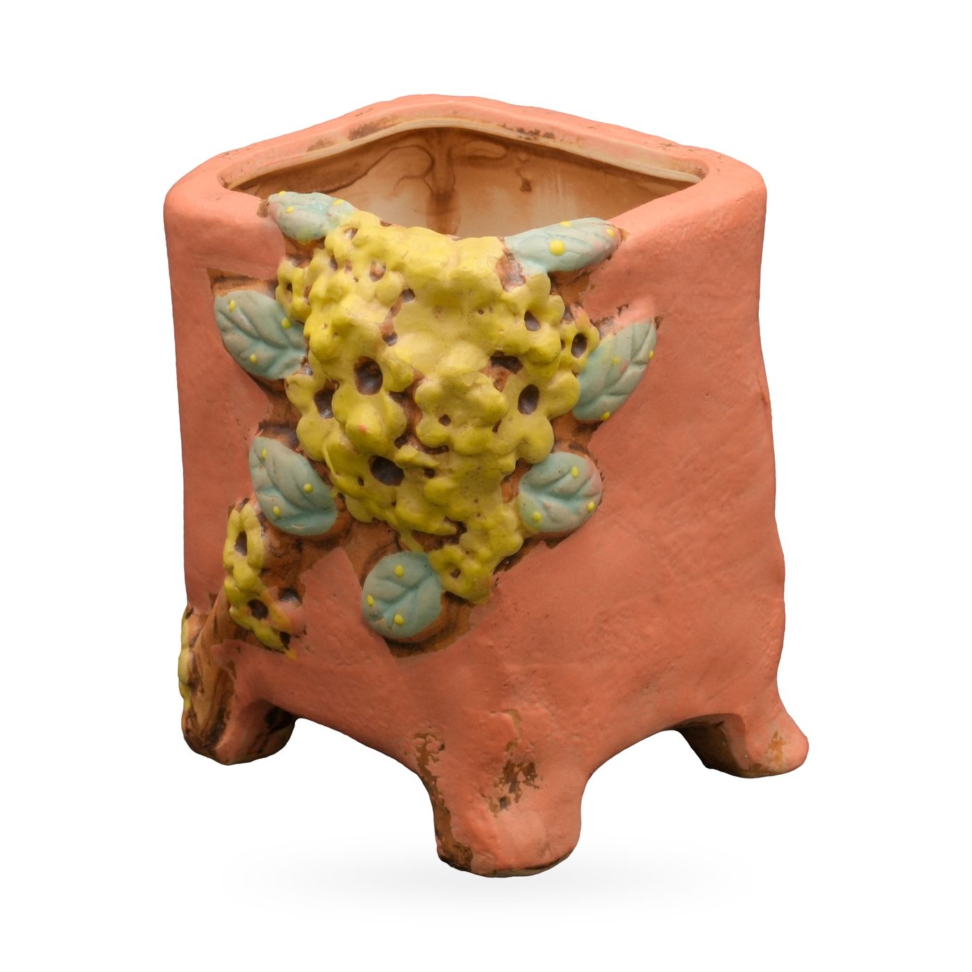 Coral-orange square footed pot with raised yellow flower and blue-green leaf relief on one corner