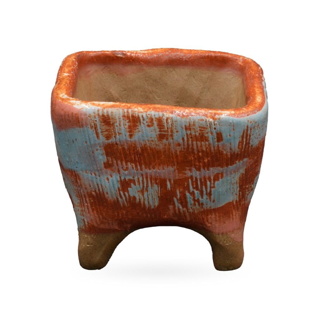 Square pot with combed texture in burnt orange and pale blue, on short clay feet