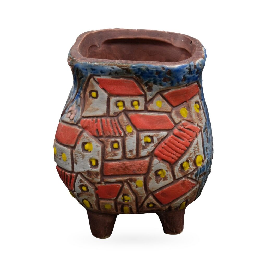 Footed succulent pot with a raised village scene of red-roofed houses and a tree on blue glaze