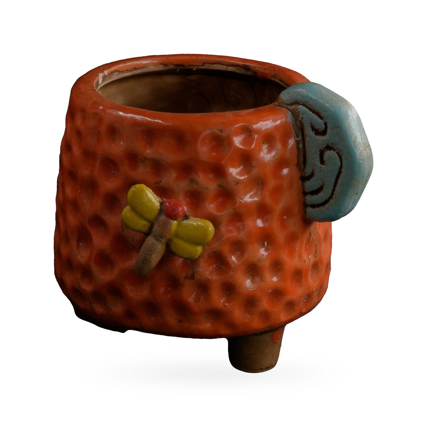 Orange dimpled footed pot with a light-blue cloud-swirl tab and yellow-winged dragonfly