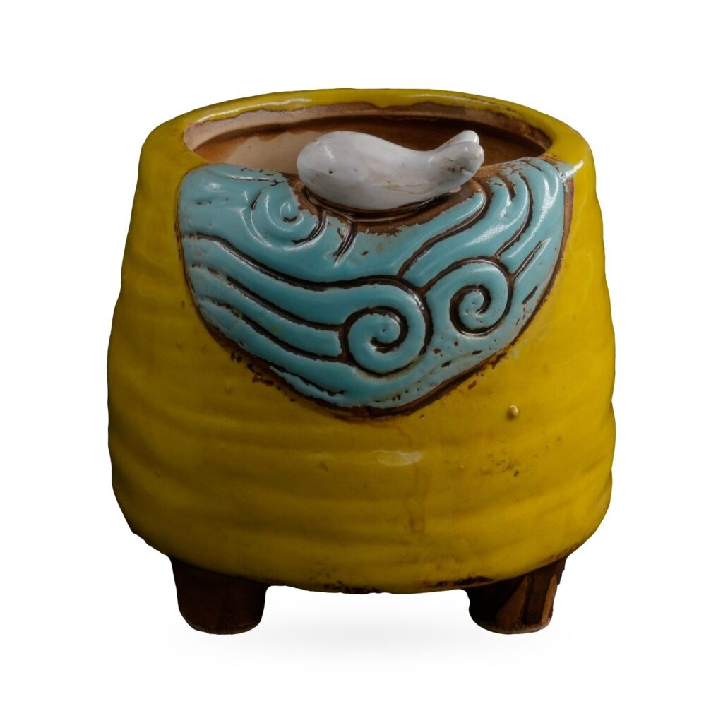 Yellow ribbed footed pot with a light-blue wave panel and small white bird on the rim