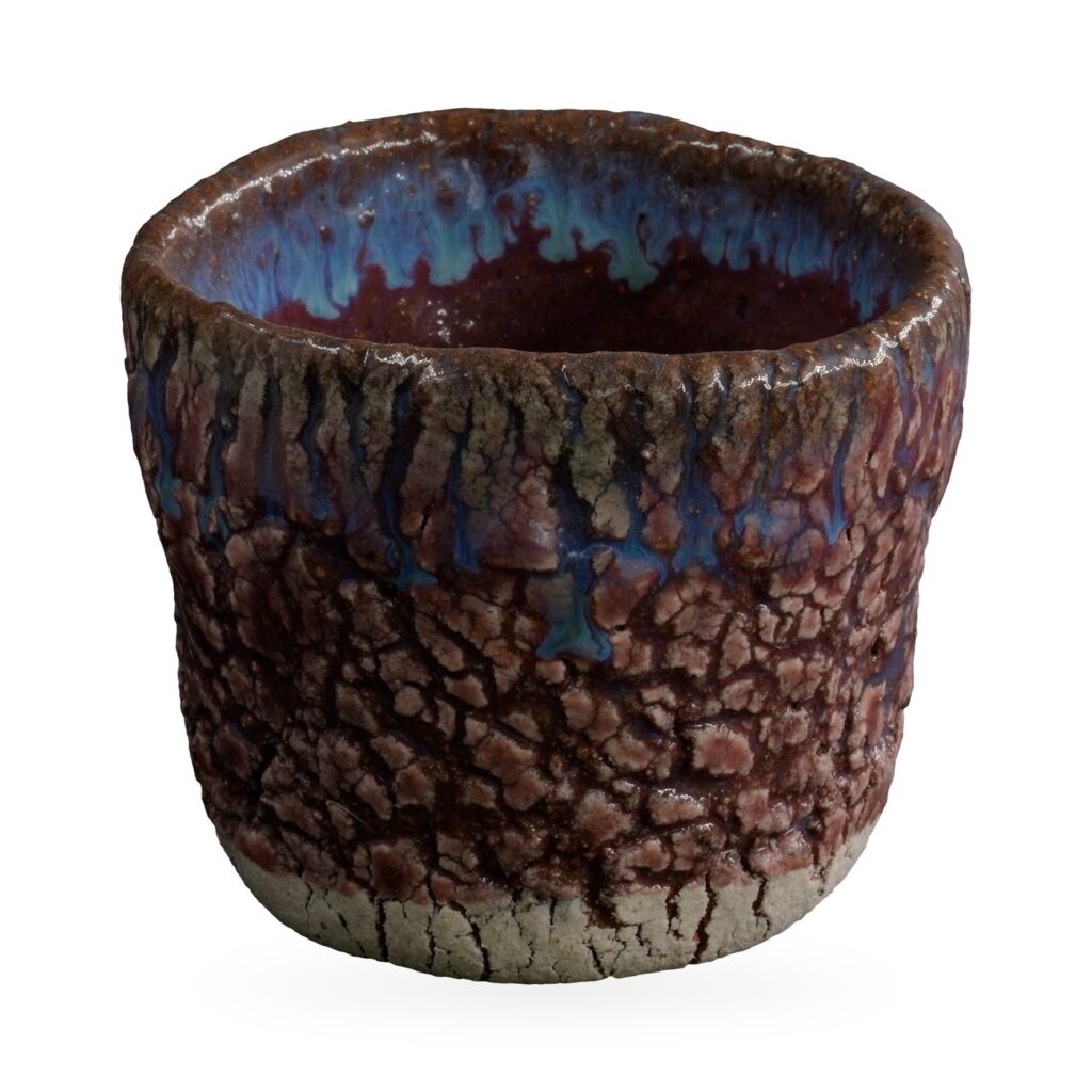 Round rustic pot with raised purple-pink crackle glaze and blue glaze drips at the rim