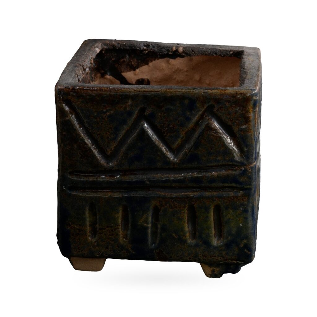 Square dark blue-black glazed pot with a textured zigzag and band pattern on small feet