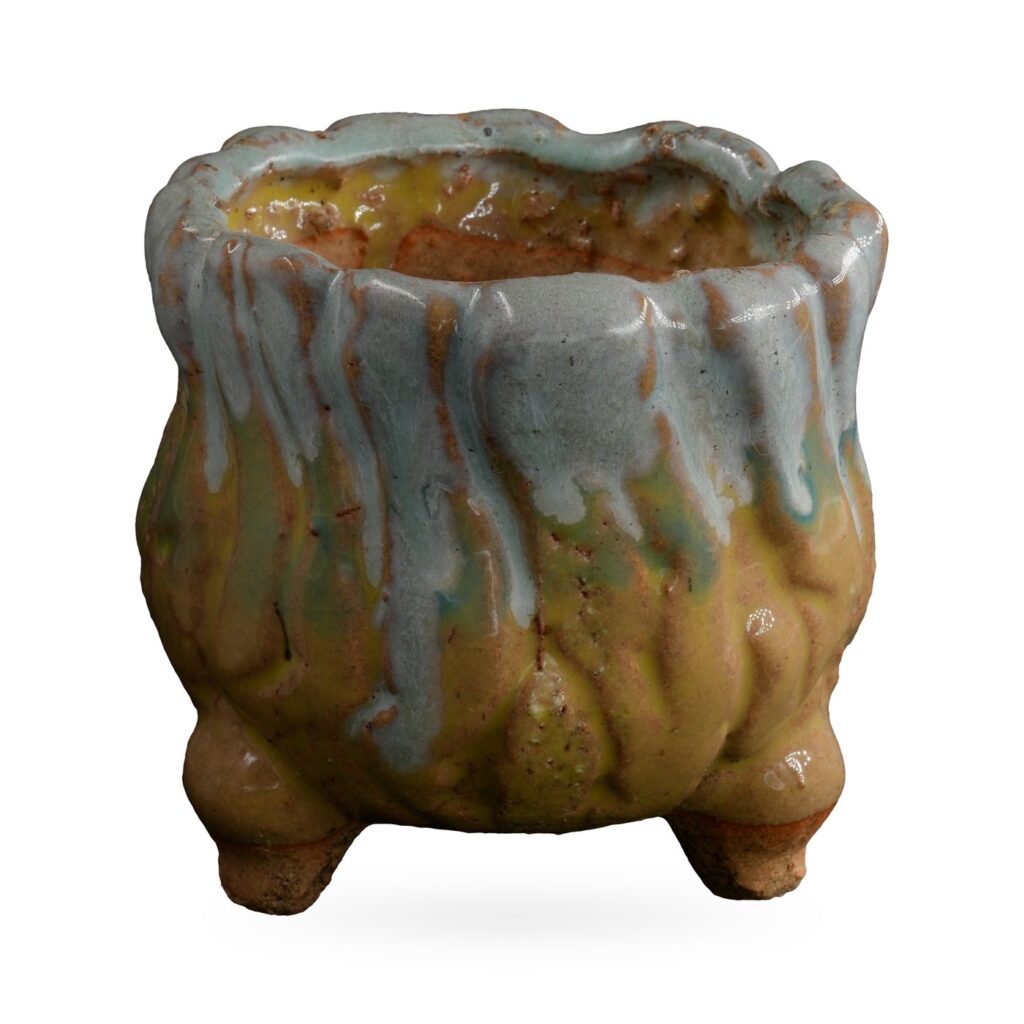 Rounded mustard-yellow footed pot with pale blue glaze dripping from a wavy rim