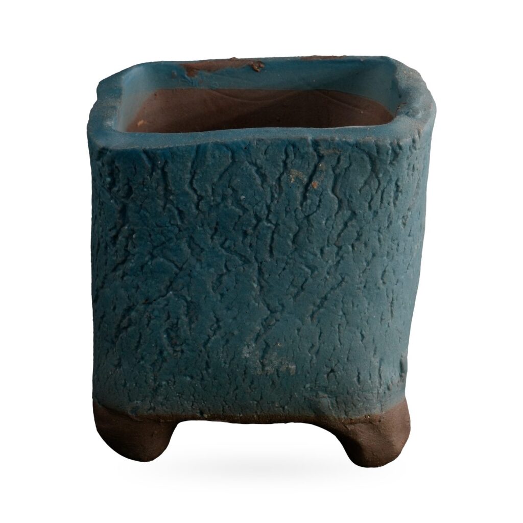 Square teal crackle-textured succulent pot with softly irregular corners and chunky brown clay feet