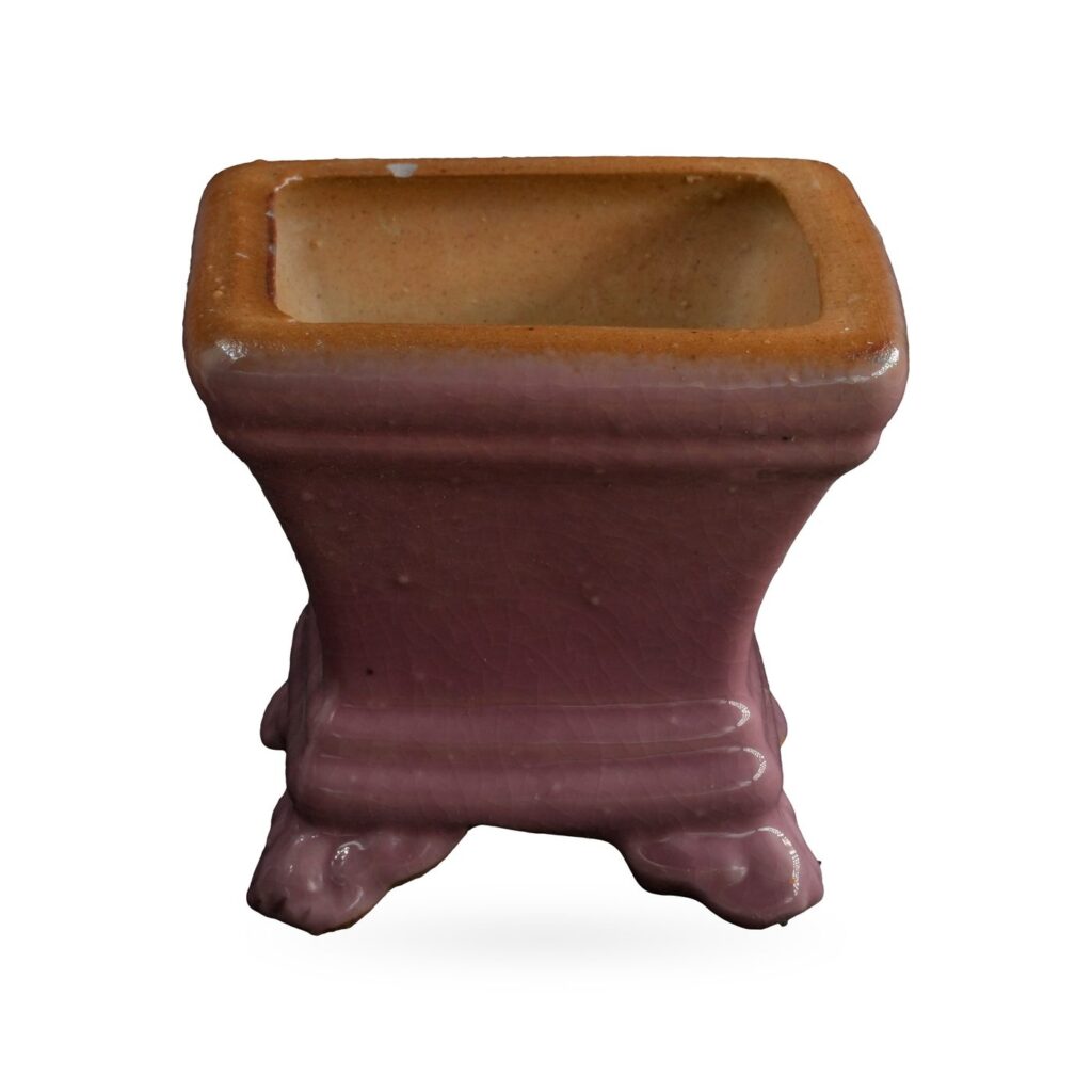 Small dusty pink square glazed pot with a tan rim, standing on cloud-shaped feet