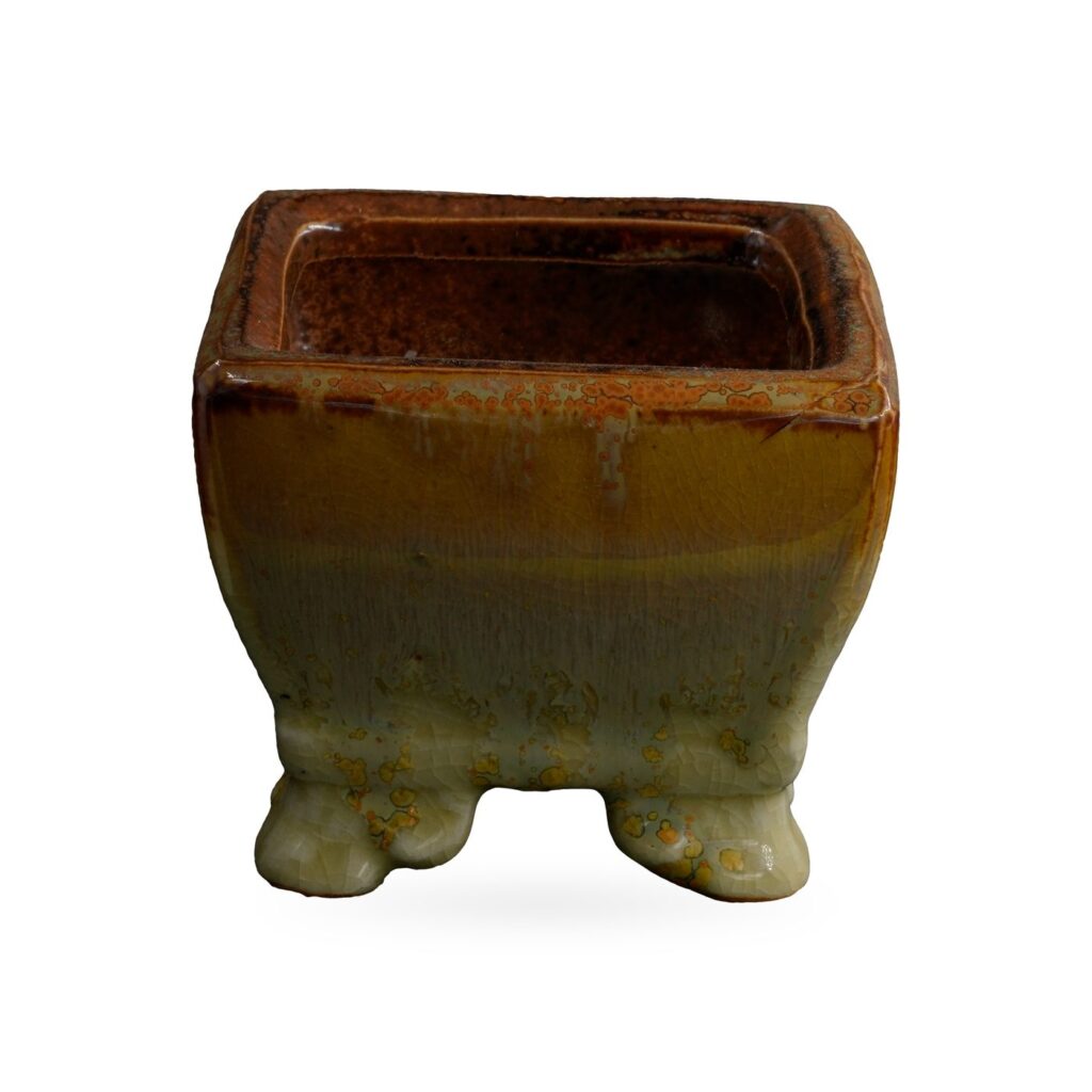 Square pot in glossy amber glaze flowing into sage green with golden speckles, on small feet