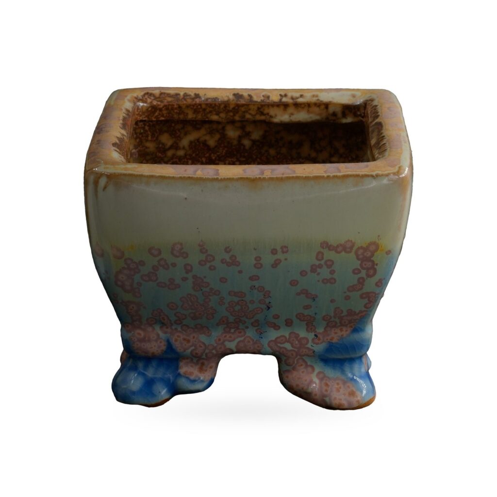 Square pot in pale cream glaze with pink-mauve speckles over soft blue, on small blue-toned feet