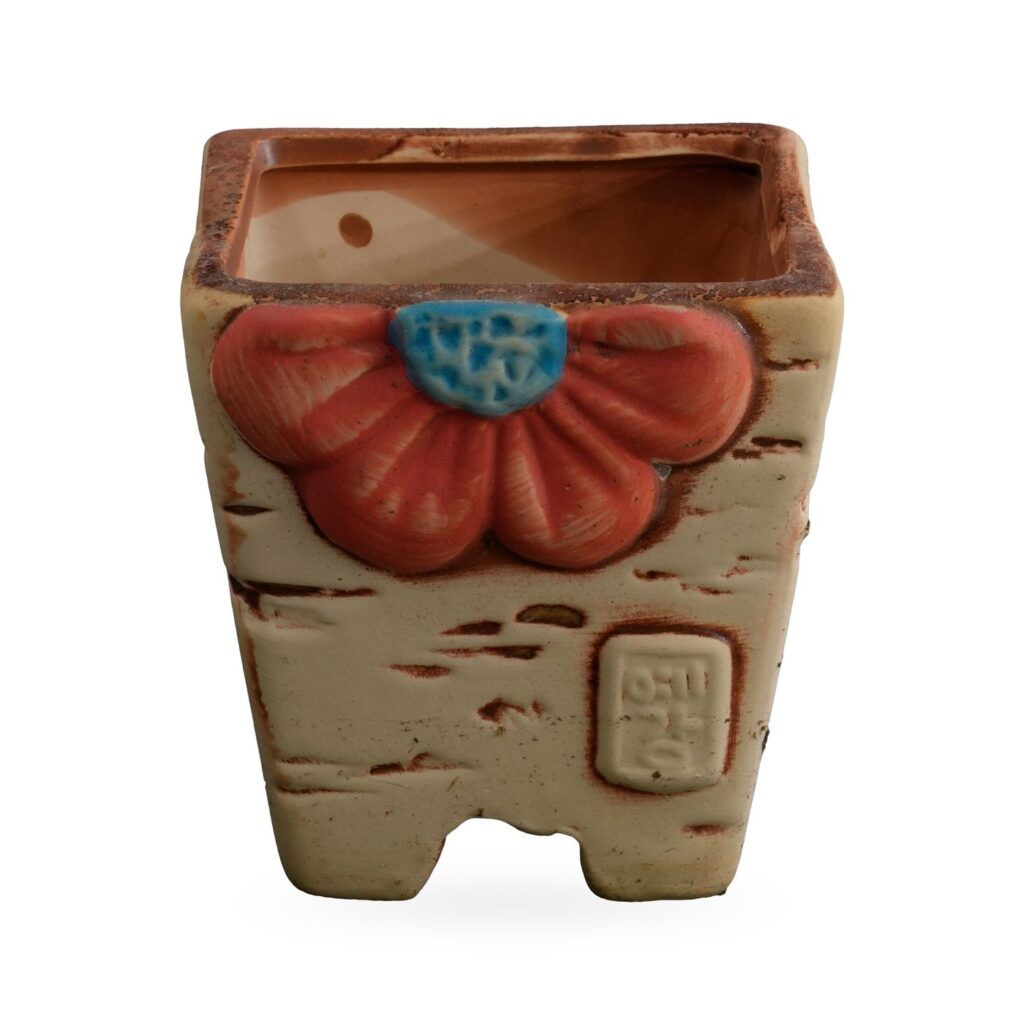 Cream tapered square succulent pot with raised orange-red flower, bark-style streaks and corner feet
