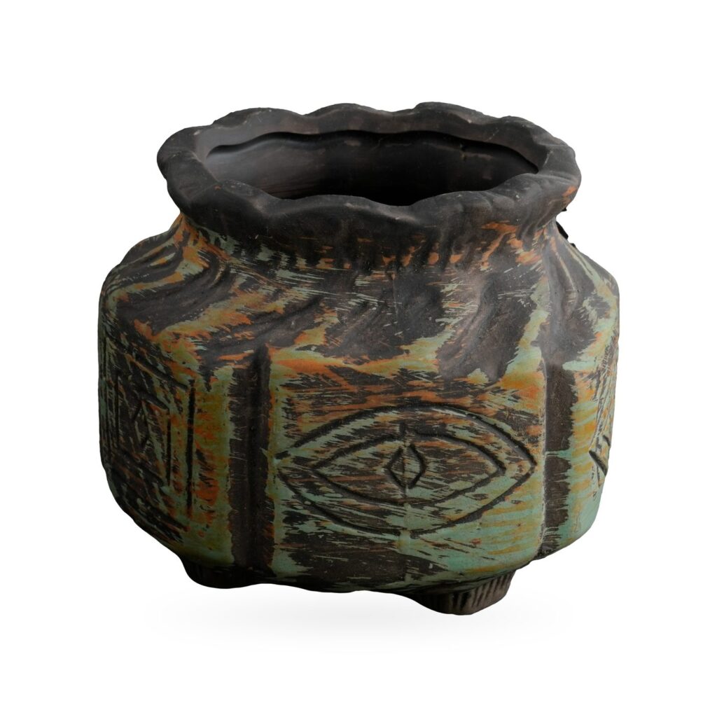 Rustic black and sage green pot with carved crescent moon, star and eye motifs and a wavy rim