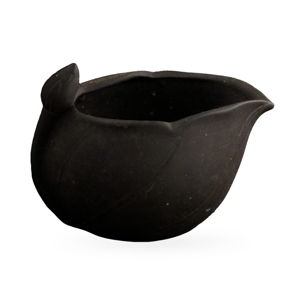 Small matte black unglazed clay pot shaped like a pitcher with a pointed spout and rounded knob