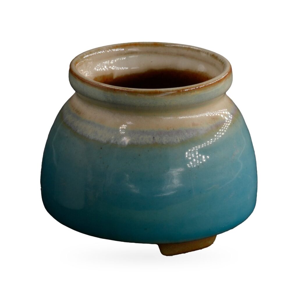 Glossy turquoise jar-shaped pot with cream shoulder and rolled neck on small feet