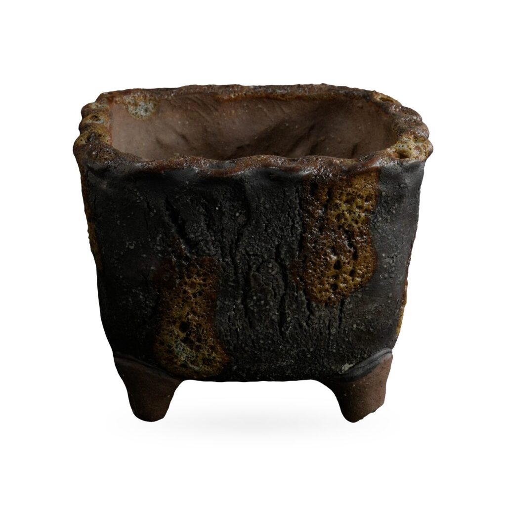 Square charcoal-black bark-texture footed pot with amber lava-style glaze patches