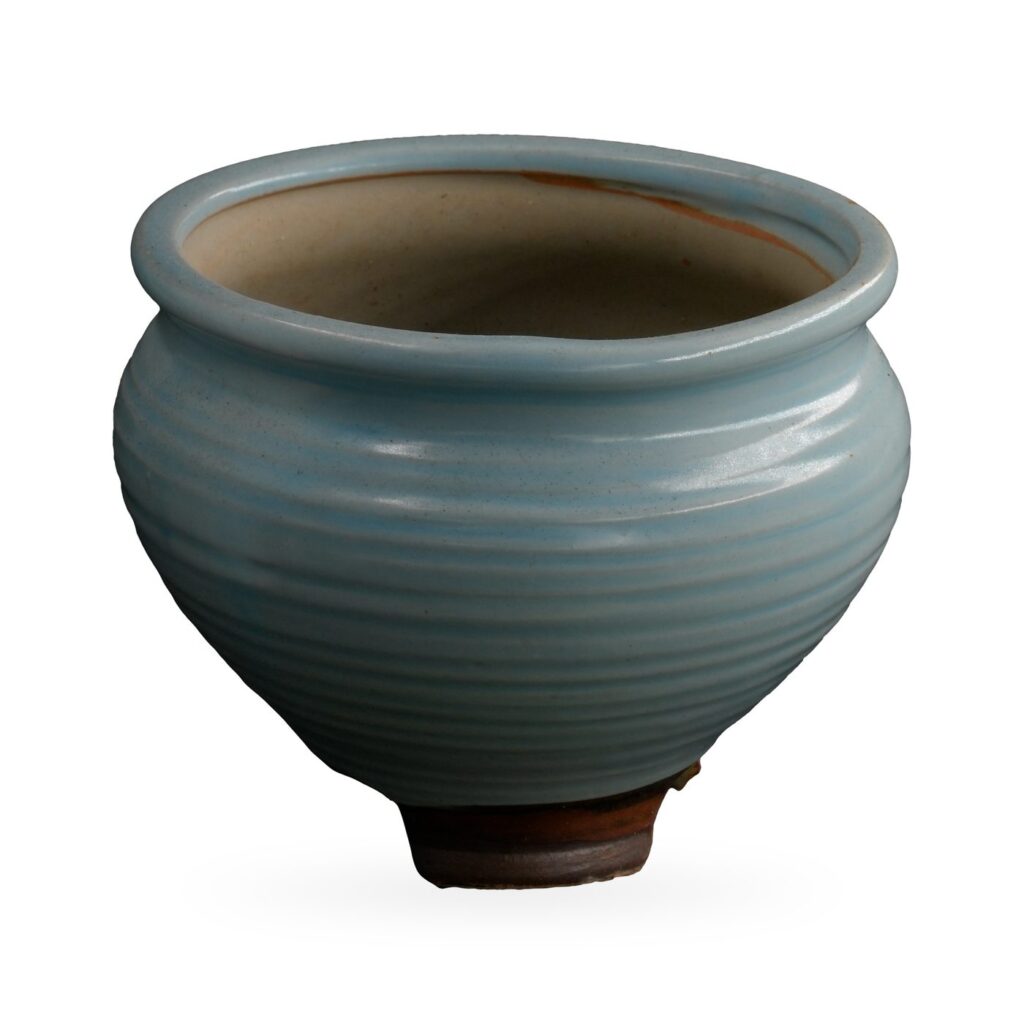 Pale blue ribbed glazed pot with rolled rim on small dark brown feet