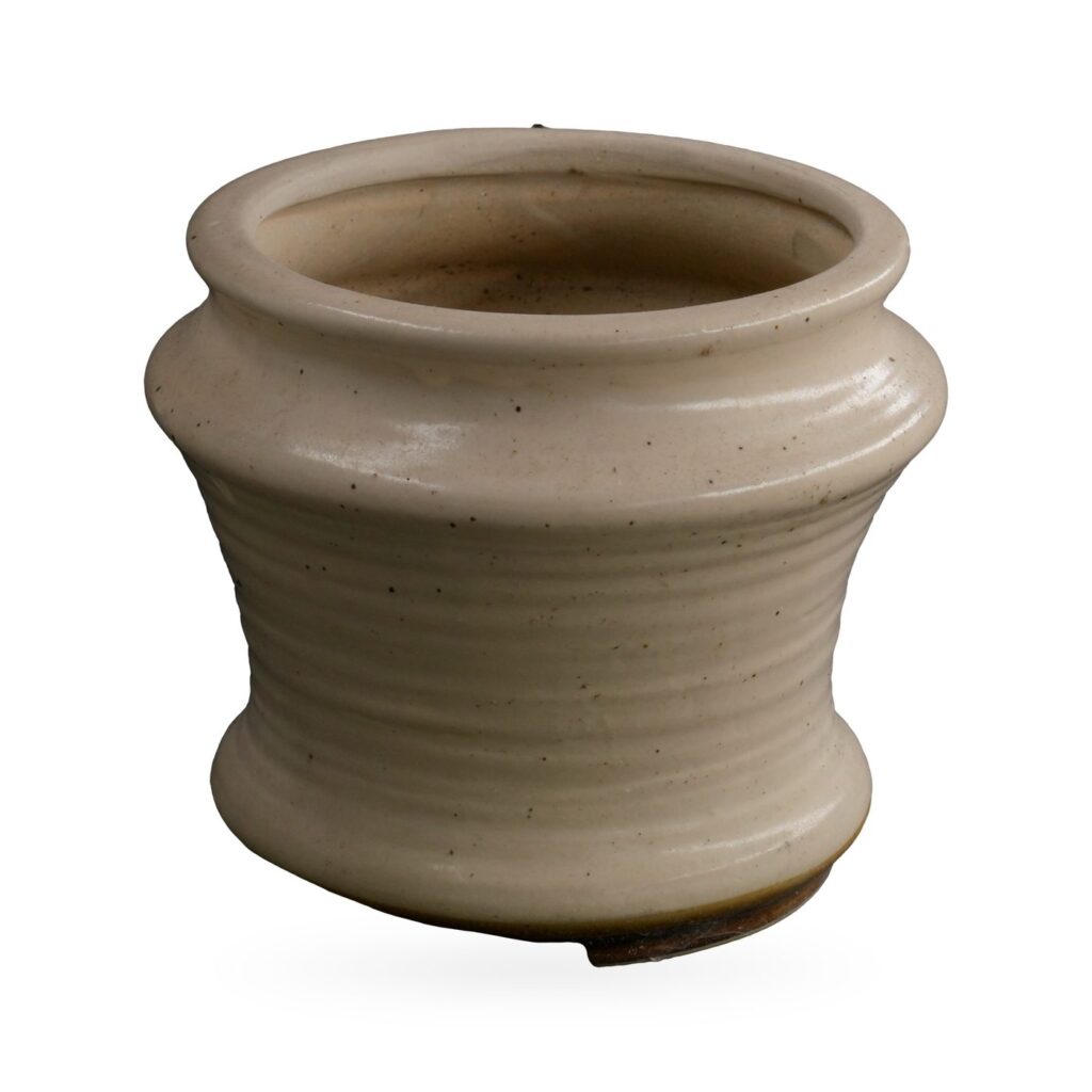 Waisted cream pot with glossy speckled glaze and rolled rim on small dark feet