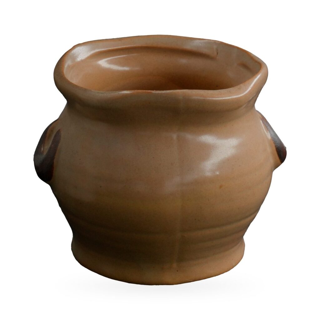 Small tan glazed pot with a wavy rim and two dark brown C-shaped lug handles