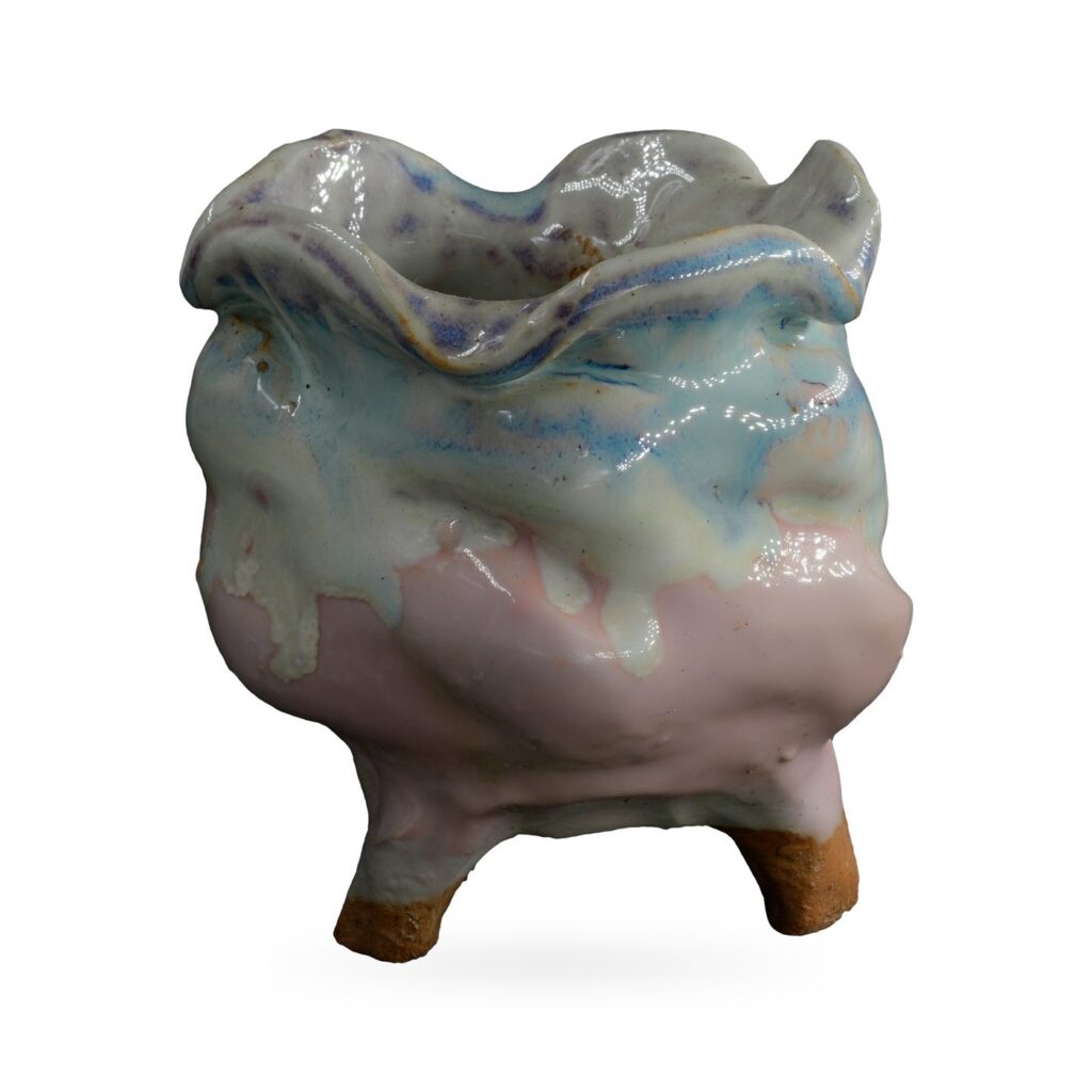 Footed pot with ruffled wavy rim and pale blue drip glaze over a soft pink body