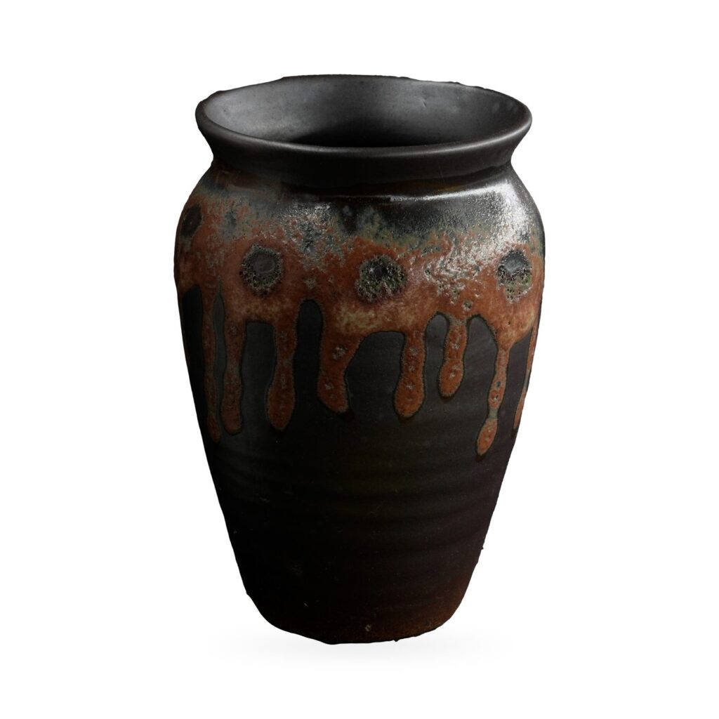 Tall black urn-shaped pot with rust-brown drip glaze and raised dotted medallions, 8.5×12cm