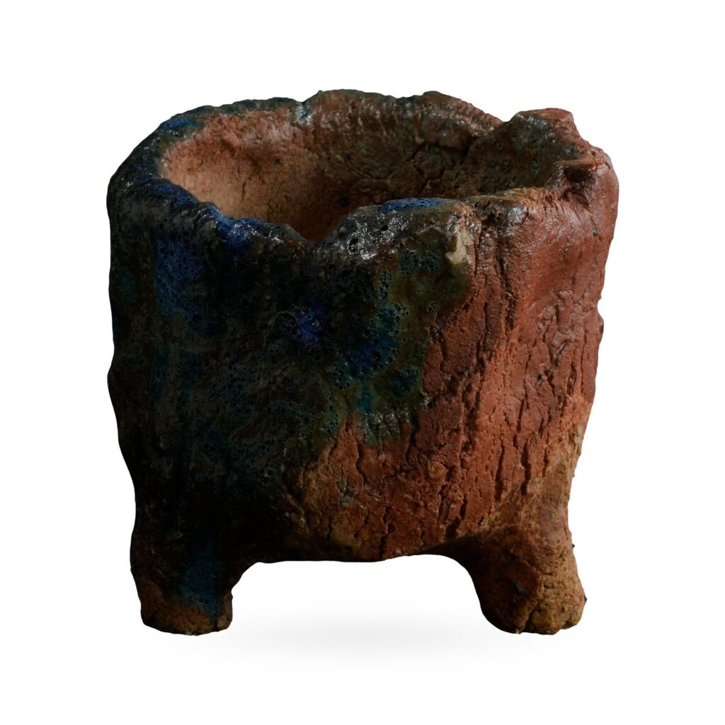 Rugged stump-like footed pot in red-brown clay with deep blue and teal glaze patches