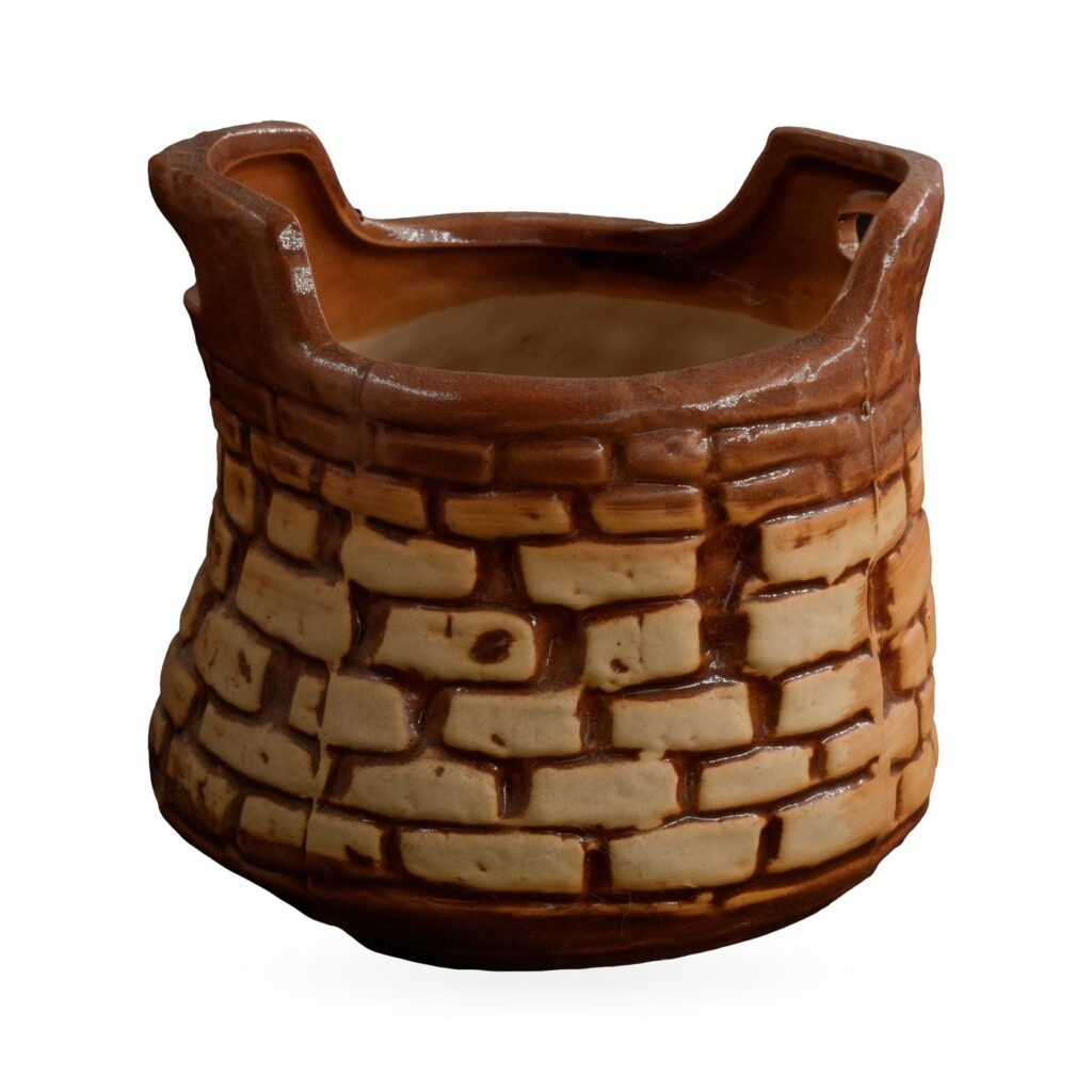 Glazed brick-pattern pot shaped like a little well, with two raised uprights on the rim