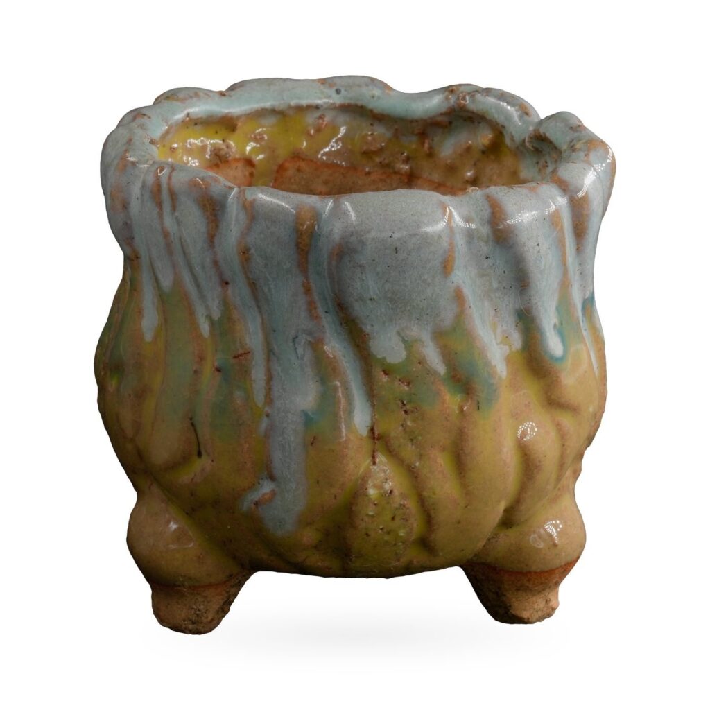 Rounded mustard-yellow footed pot with pale blue glaze dripping from a wavy rim