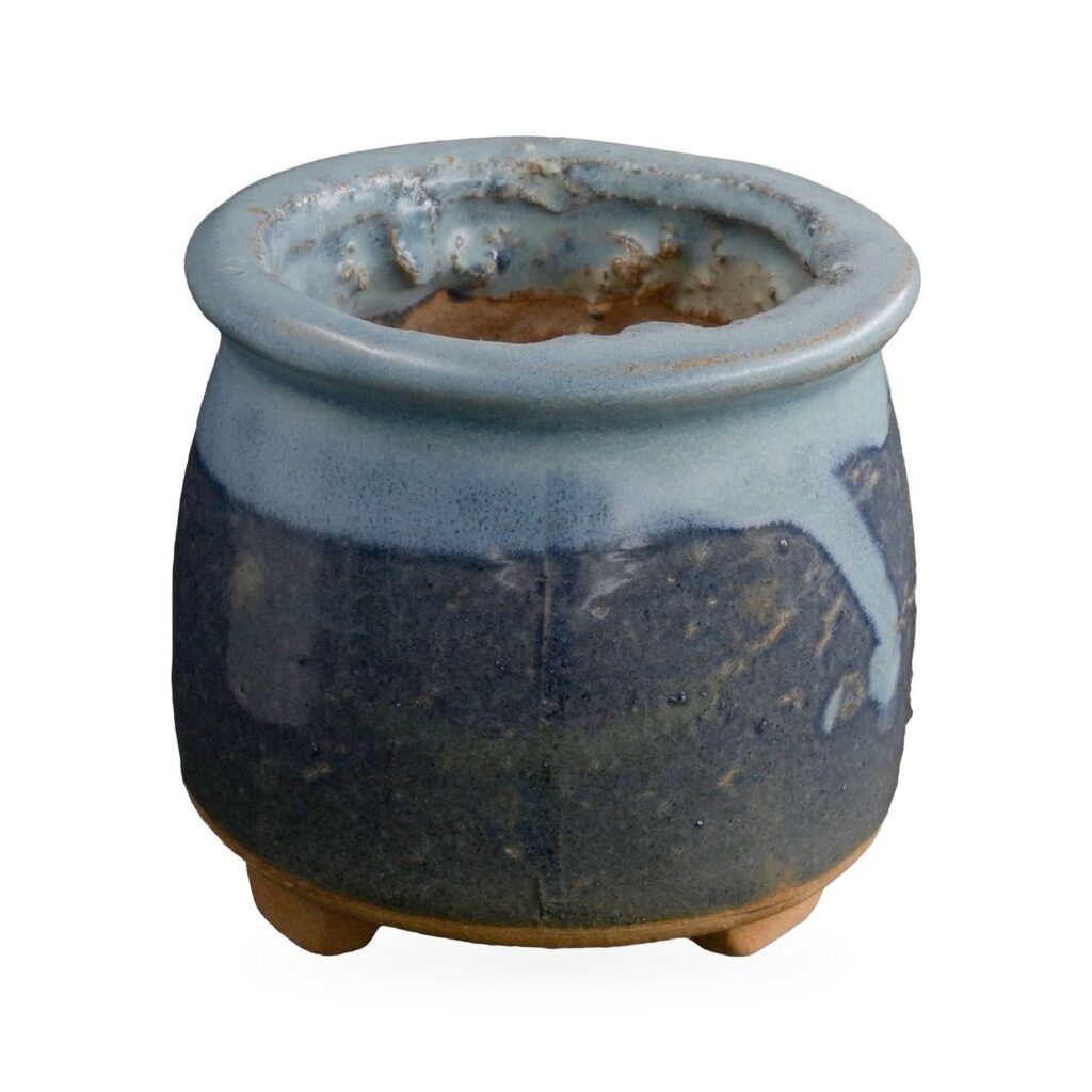 Navy blue footed succulent pot with glossy pale sky-blue glaze dripping down from the rim