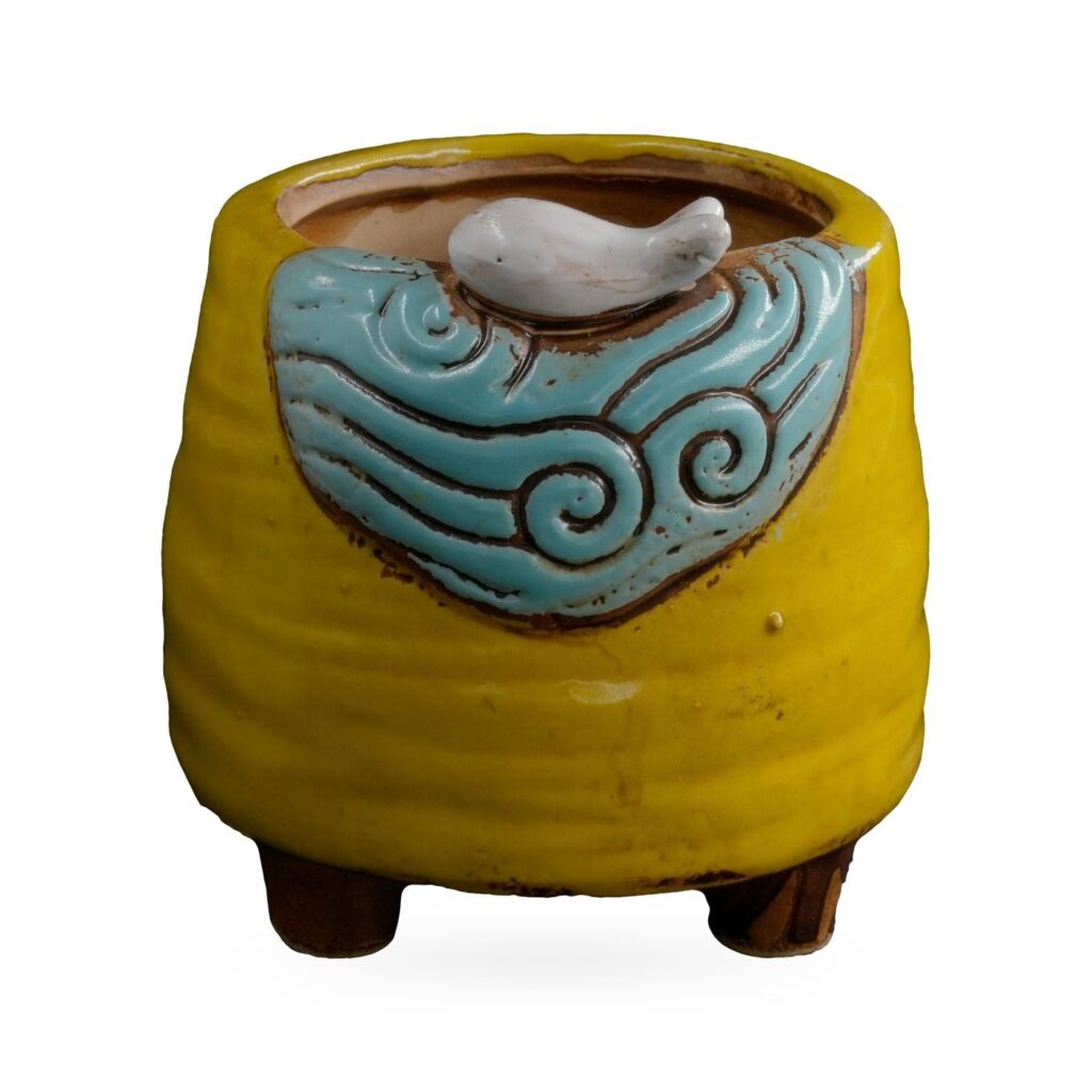 Yellow ribbed footed pot with a light-blue wave panel and small white bird on the rim