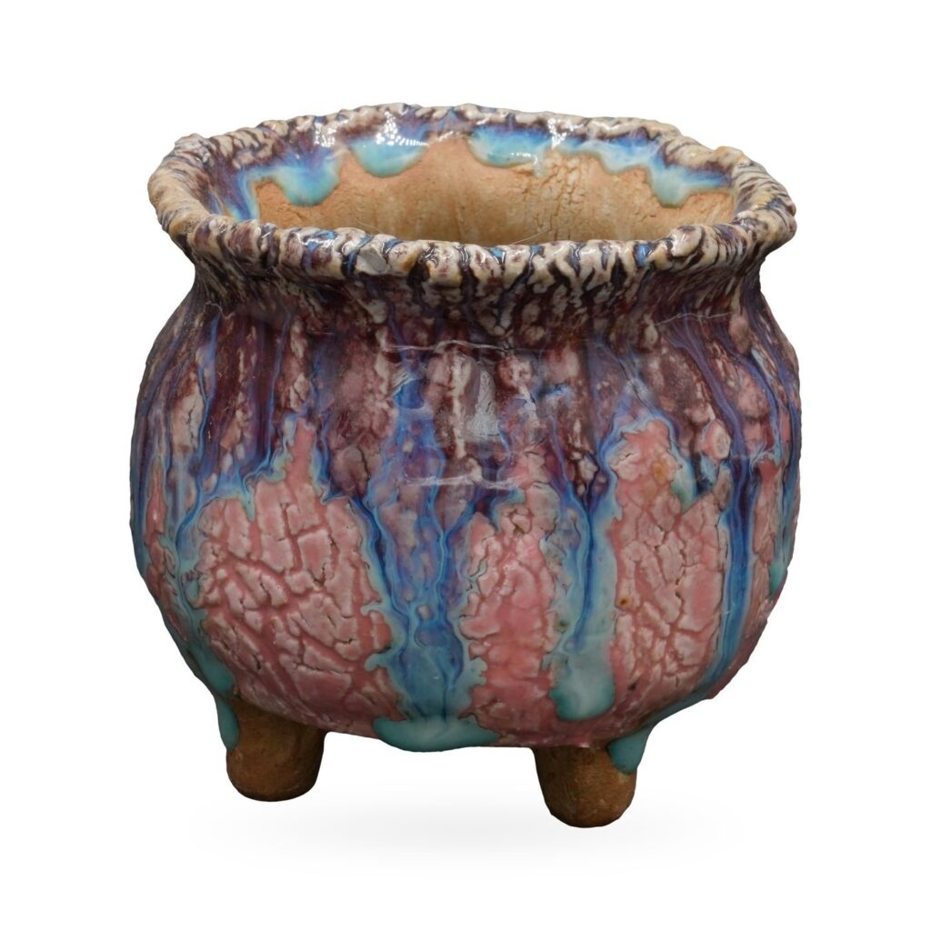 Round footed pot with crackled pink body, purple and turquoise drip glaze and a textured rolled rim