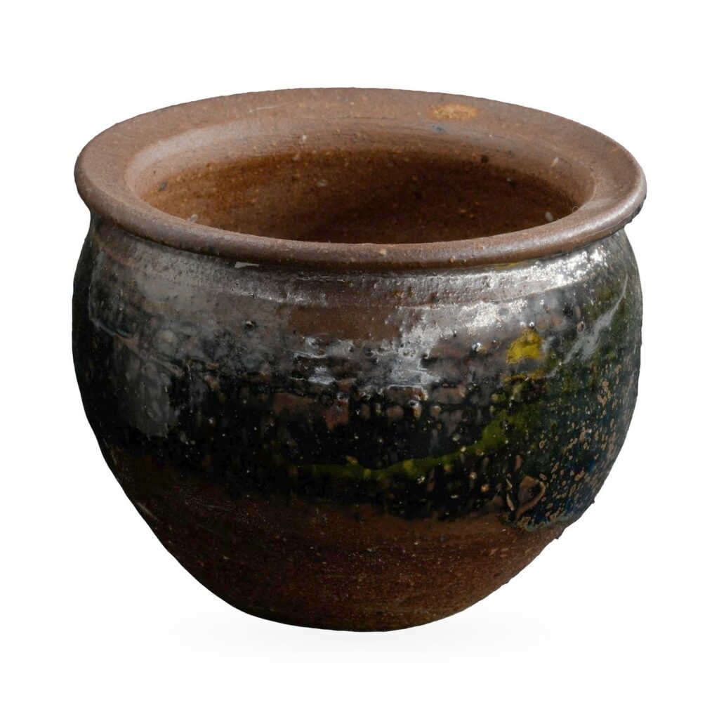 Round pot in glossy black glaze with rust-brown speckles, a wide flared brown rim and bare clay base