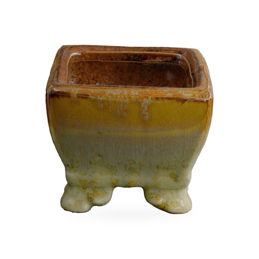 Square pot in glossy amber glaze flowing into sage green with golden speckles, on small feet