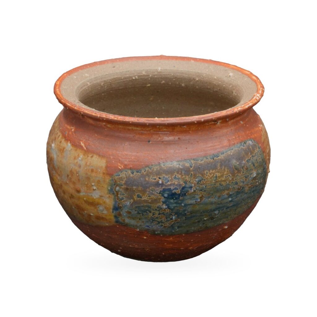 Round-bellied rust-red pot with ochre and blue-grey glaze patches and a flared rim