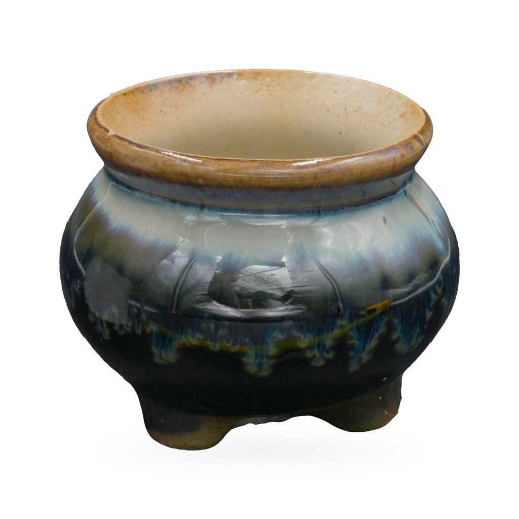 Rounded footed pot in glossy navy reactive glaze with pale blue drips and an amber rolled rim