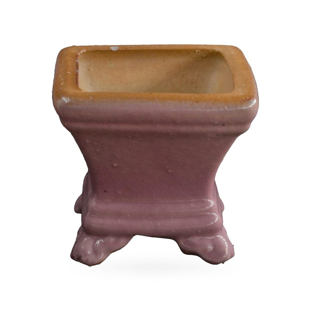 Small dusty pink square glazed pot with a tan rim, standing on cloud-shaped feet