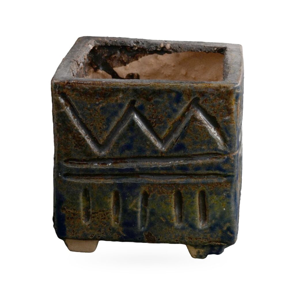 Square dark blue-black glazed pot with a textured zigzag and band pattern on small feet