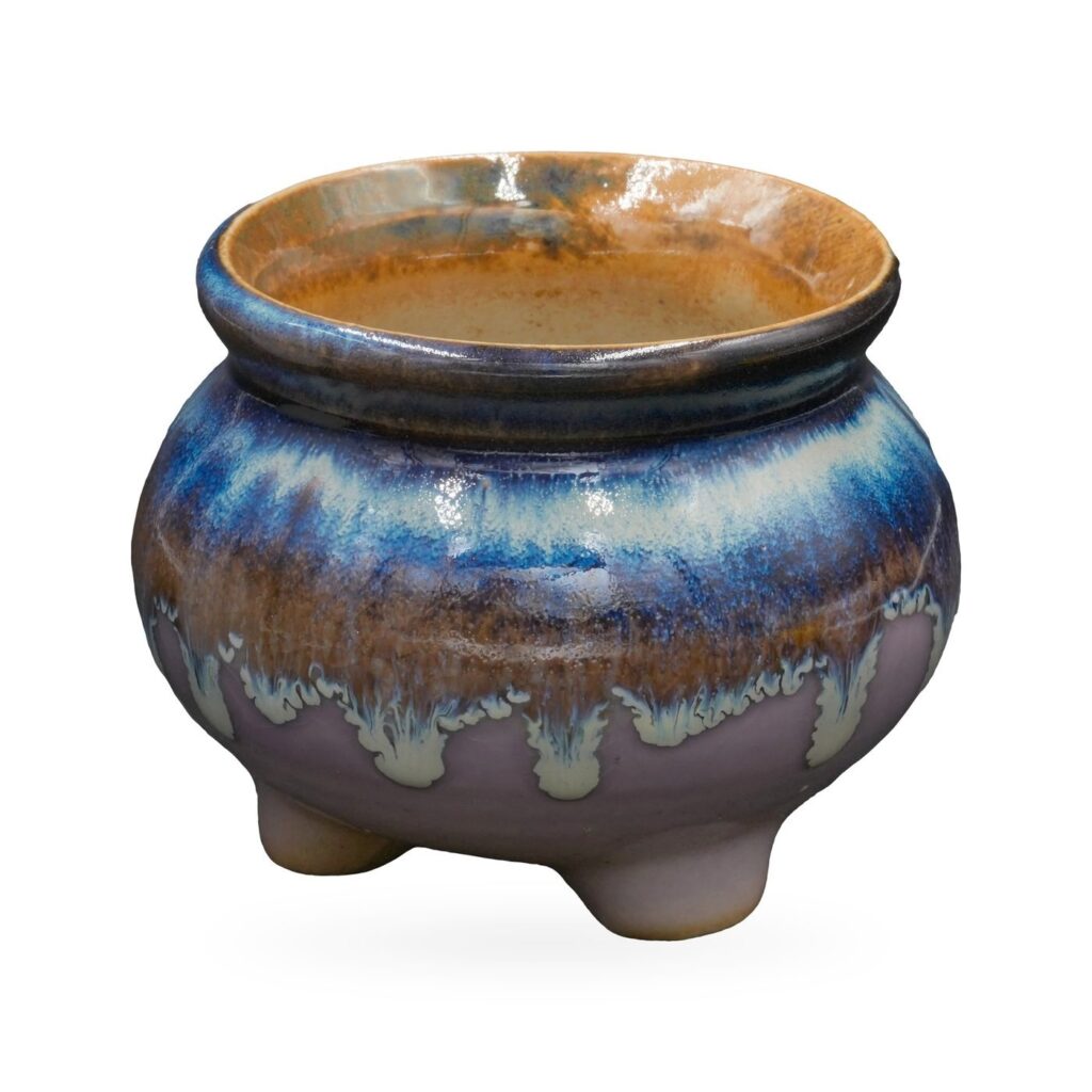 Footed round pot with glossy cobalt-blue glaze dripping over lavender and a rust-amber rim