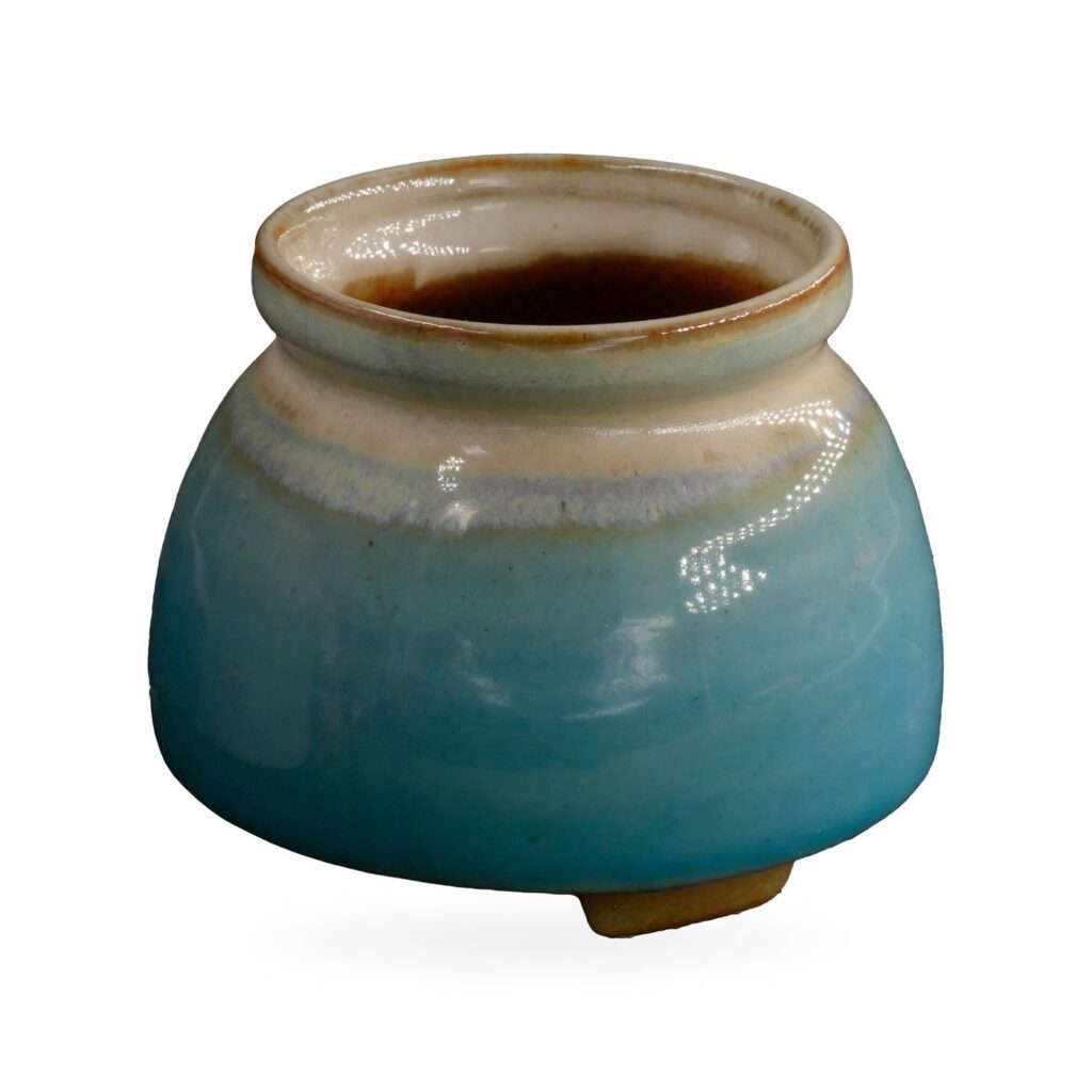 Glossy turquoise jar-shaped pot with cream shoulder and rolled neck on small feet