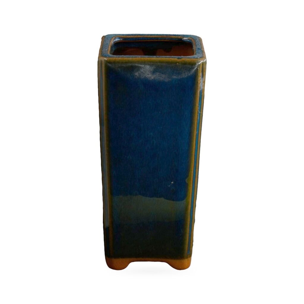 Tall slim square pot in glossy navy-blue glaze with amber-brown edges and small corner feet