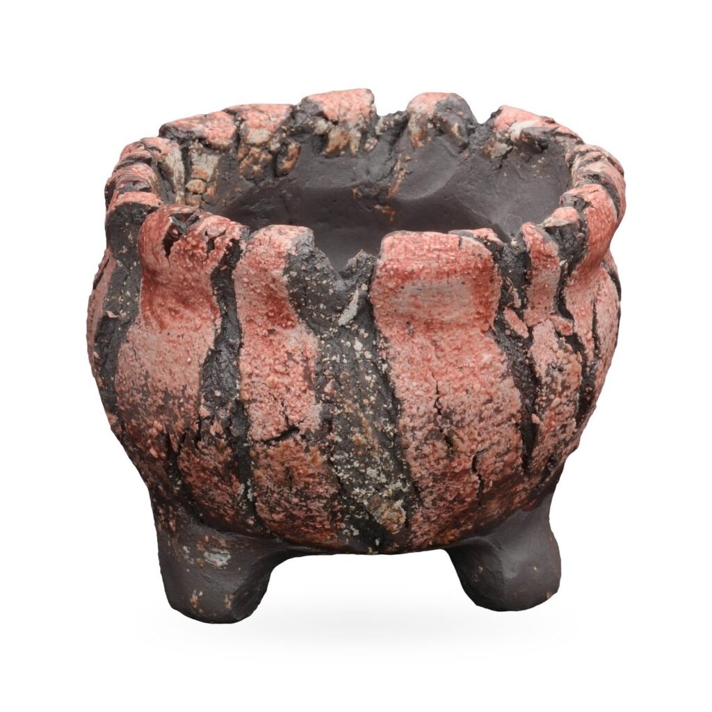 Round coral-pink and charcoal striped textured pot with scalloped rim and small dark feet