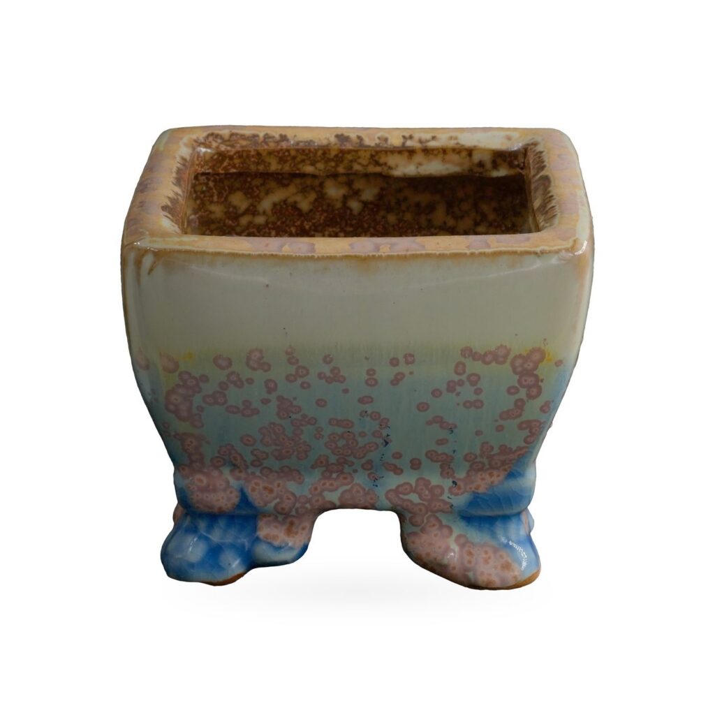 Square pot in pale cream glaze with pink-mauve speckles over soft blue, on small blue-toned feet
