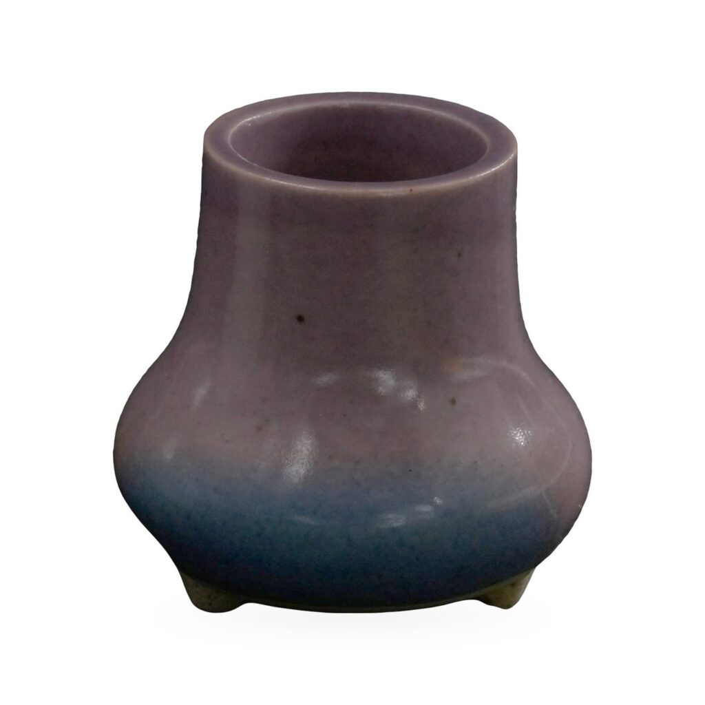 Tiny purple vase-shaped succulent pot fading to blue at the base, on small cream feet