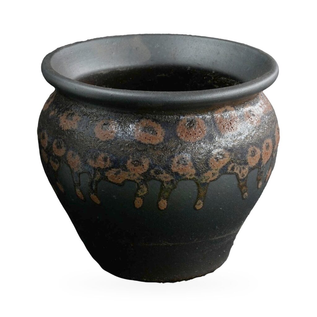 Round matte black pot with a rust-orange spotted drip glaze band and rolled rim