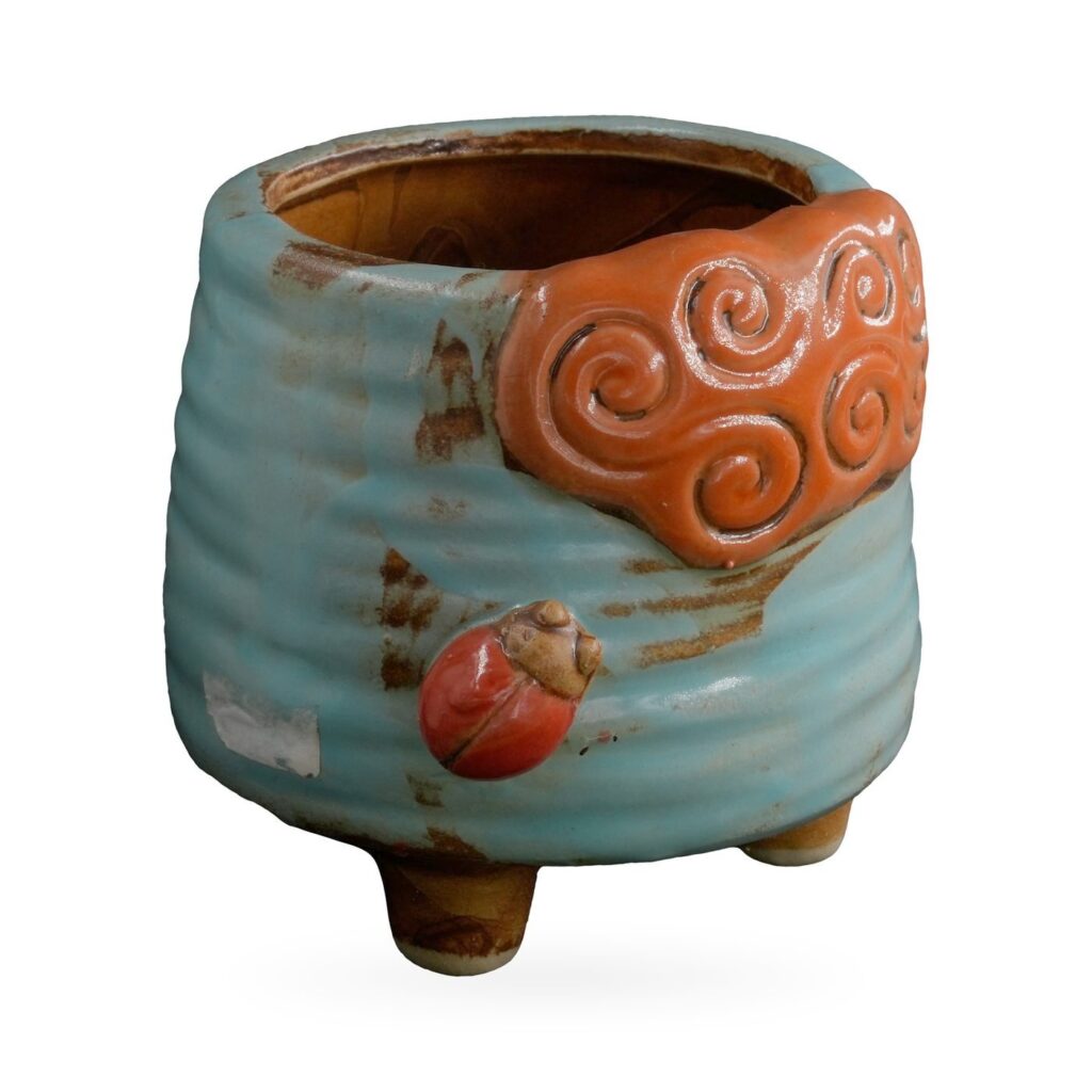 Light-blue ribbed footed pot with an orange cloud-swirl panel and red ladybird