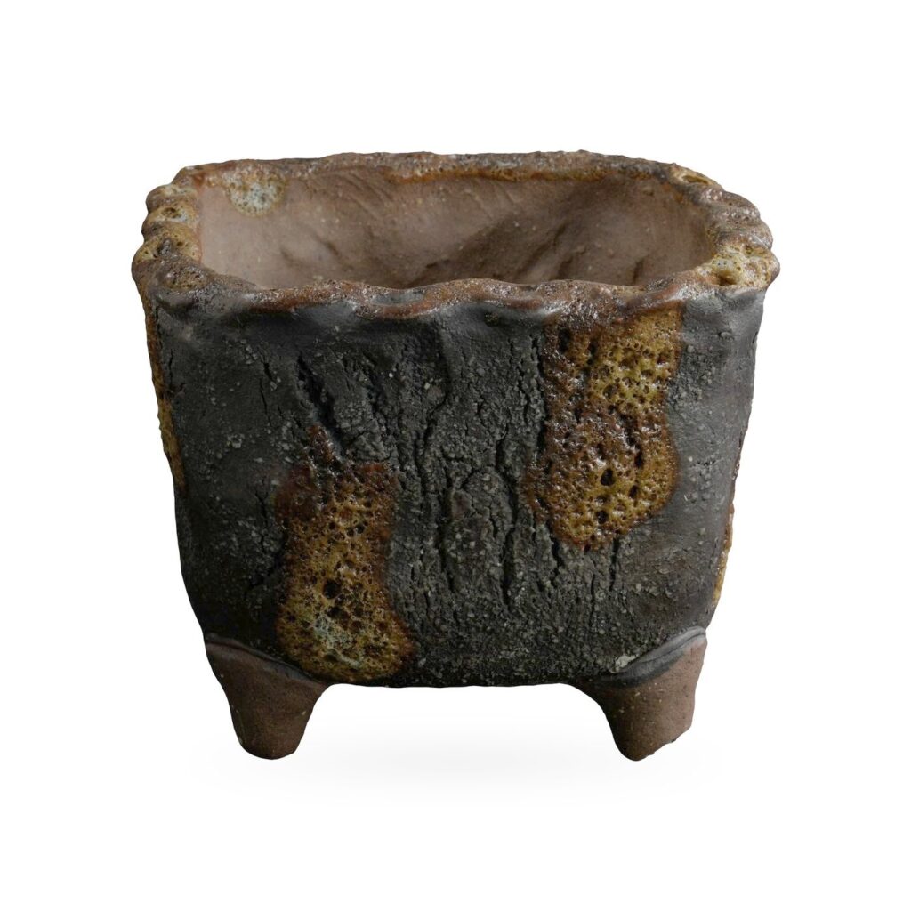 Square charcoal-black bark-texture footed pot with amber lava-style glaze patches
